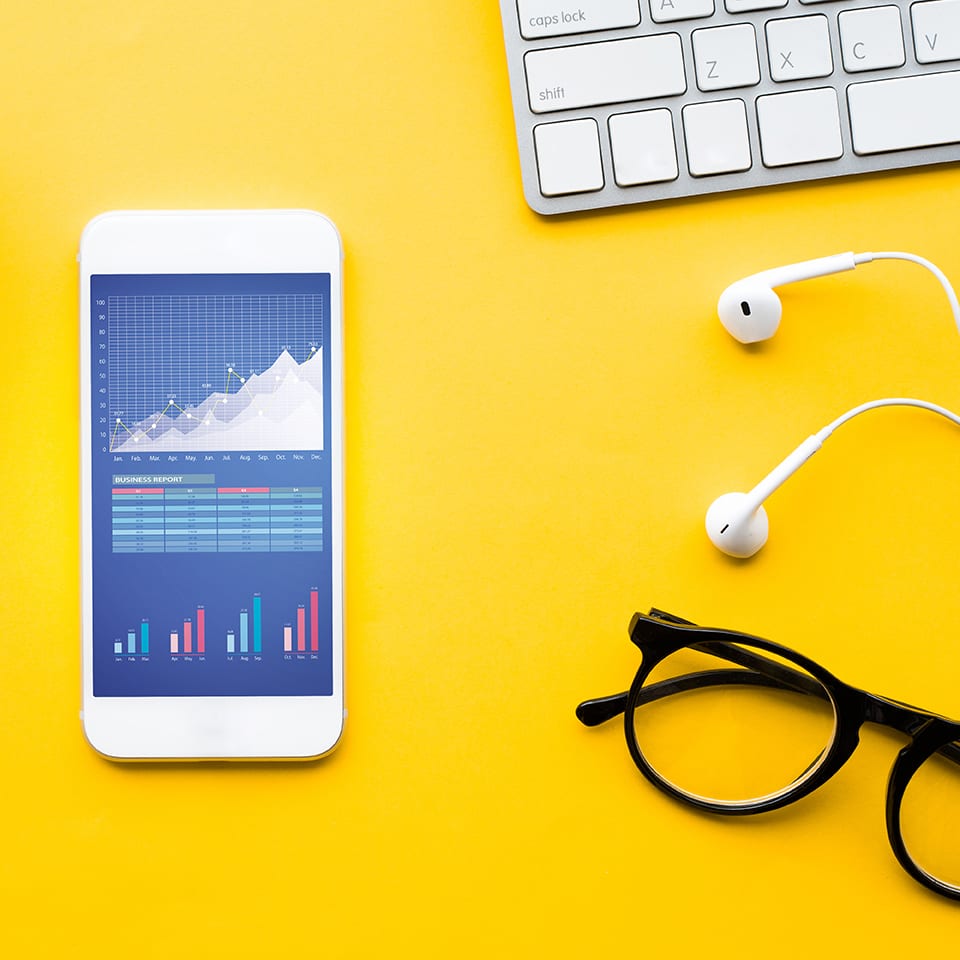 Top view of office desk table with graph chart on mock up smartphone,supplies on color background.flat lay design.business concepts ideas