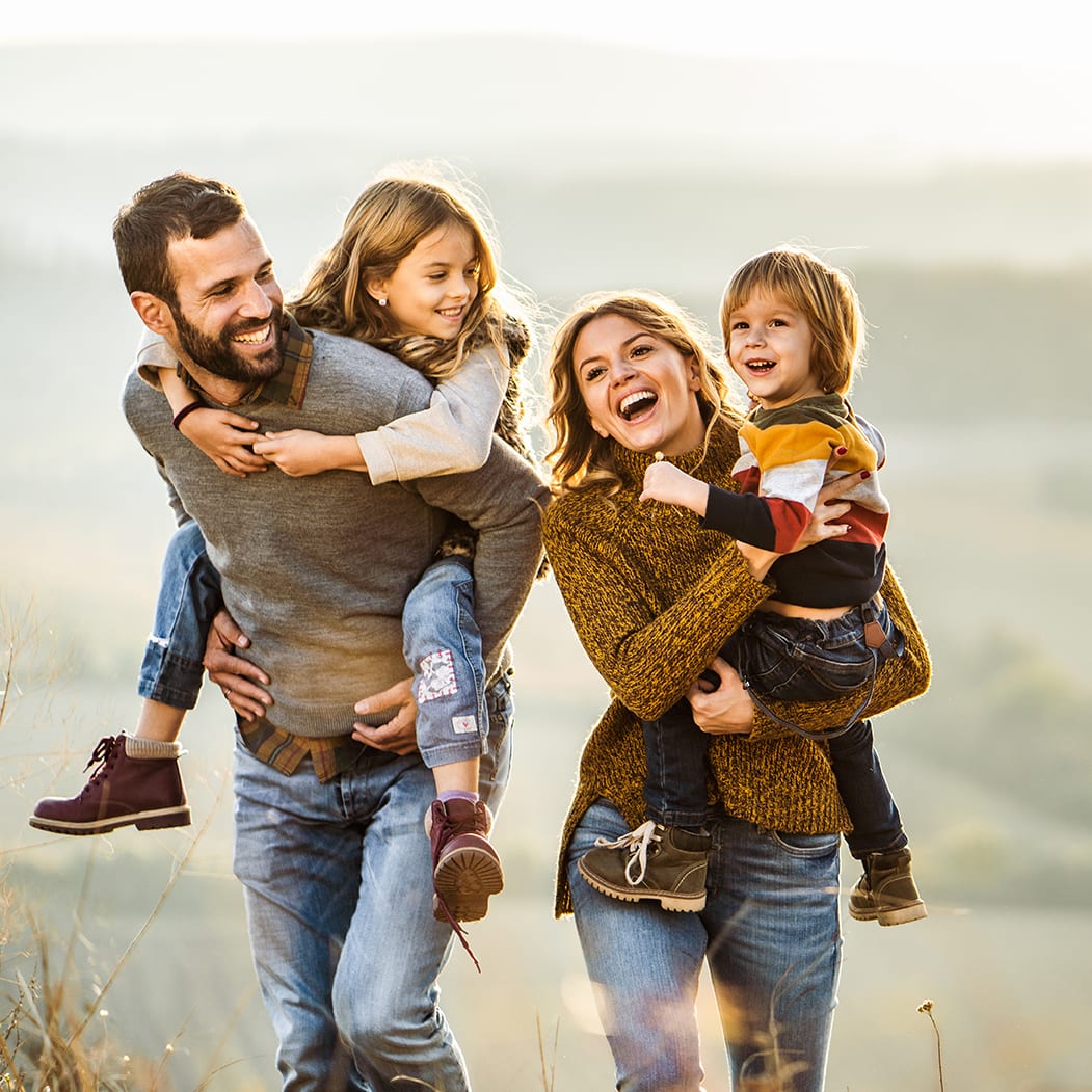 A young happy family with parents and two kids enjoying an autumn walk on a hill