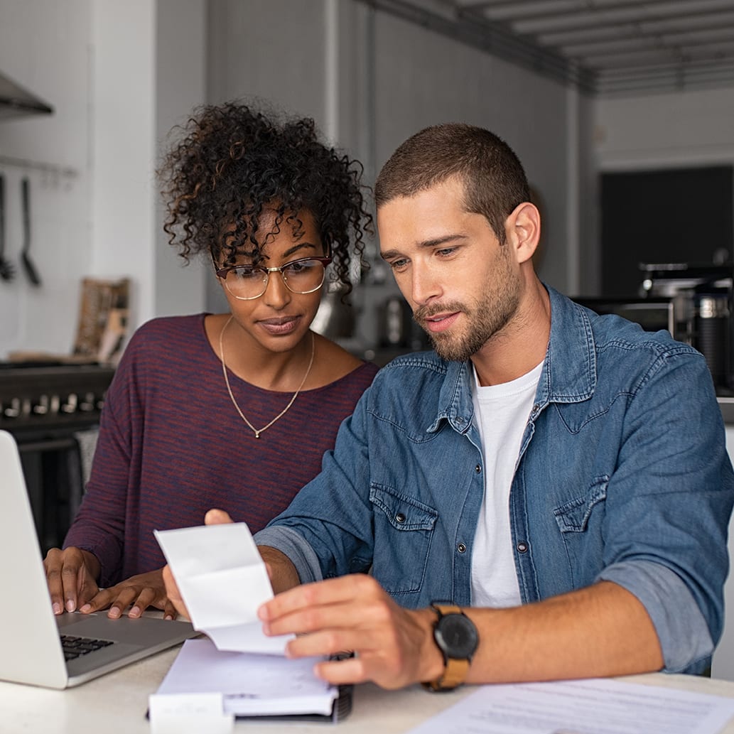 couple checking bills while managing accounts on home banking app.