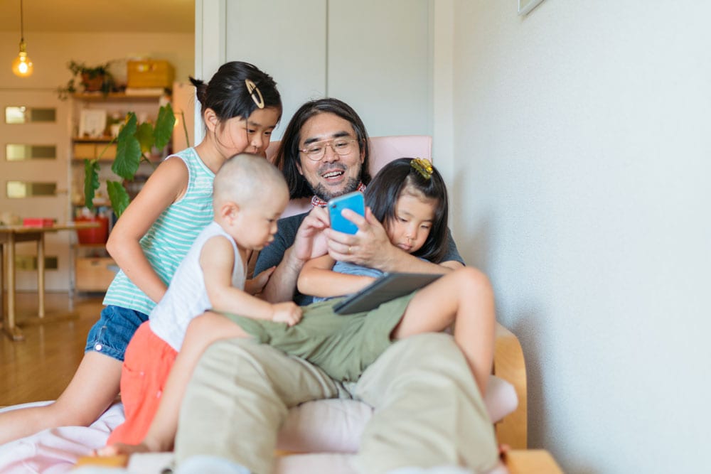 family sitting looking at dads phone