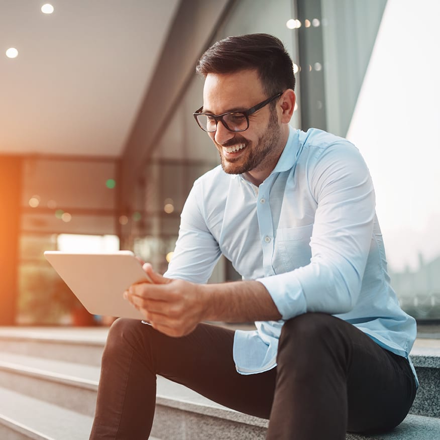 Portrait of businessman in glasses holding tablet outdoors