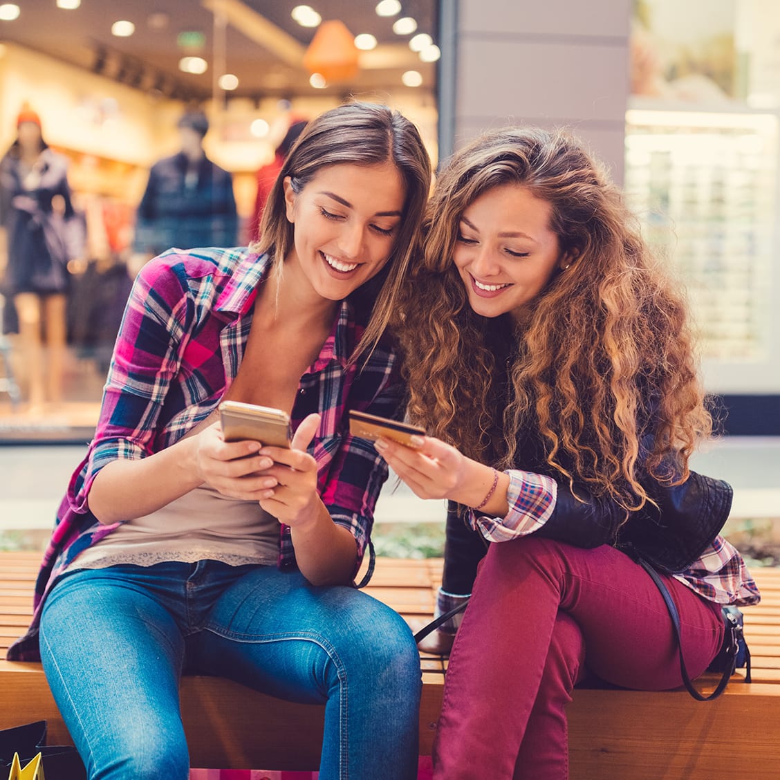 Young women in the mall using credit card for online shopping +++++ Note for the inspector : Credit card is fake and made especially for the photosession +++++